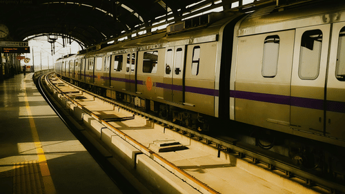 A metro stopped at an empty station, with light entering through windows and the tunnel.