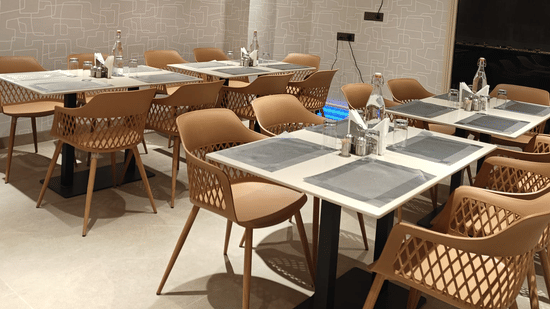 Modern indoor dining area at Hotel Bluestone Prime featuring neatly arranged tables with place settings, cushioned chairs, warm ambient lighting, and a clean contemporary design. The spacious layout offers a comfortable atmosphere suitable for relaxed meal