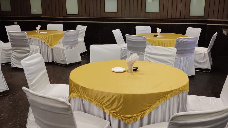 Corner view shot of the Banquet Hall featuring a round table with yellow table cloth at Hotel Gold, Panipat.