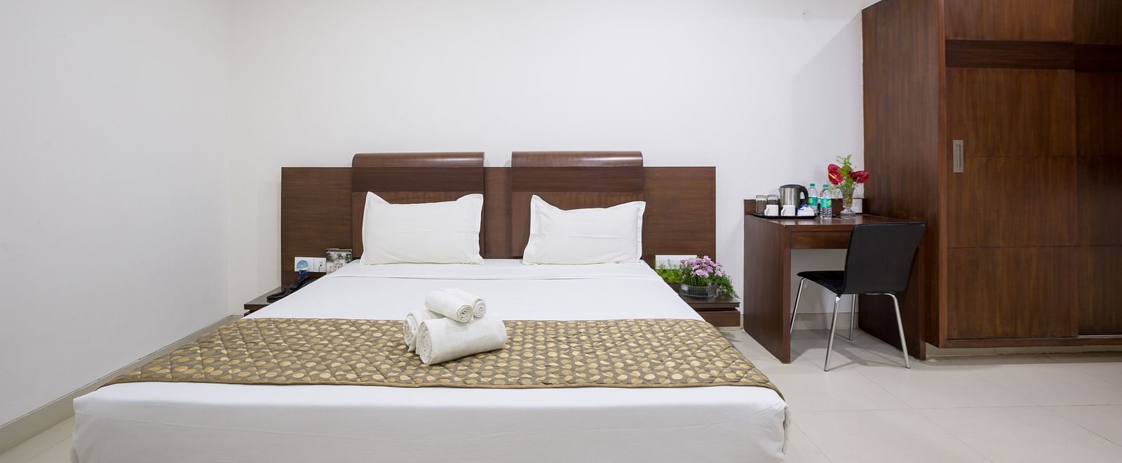 A comfortable room with a bed, bedside tables, and a wardrobe against a white wall - Sanctum Suites BEL Road, Bangalore