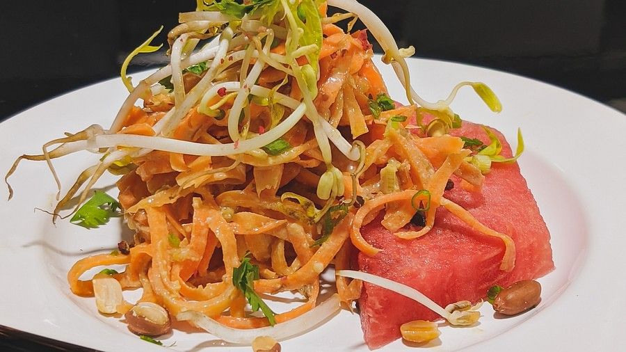 shredded vegetables, a slice of watermelon and peanuts on a plate