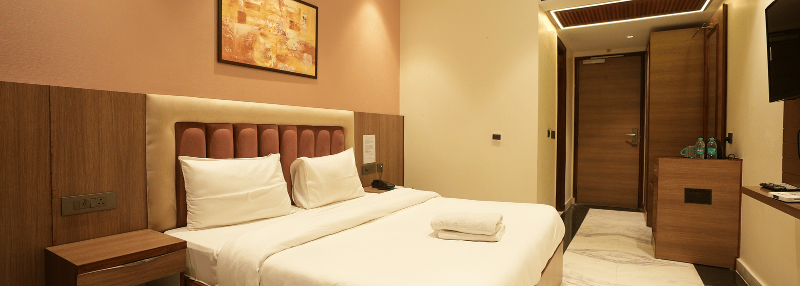 Bed and bright accent wall decor with a minibar station at Lime Tree Hotel Near India Expo Mart, Greater Noida.