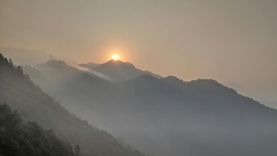 Sunrise over misty mountains, with a warm glow on the horizon.