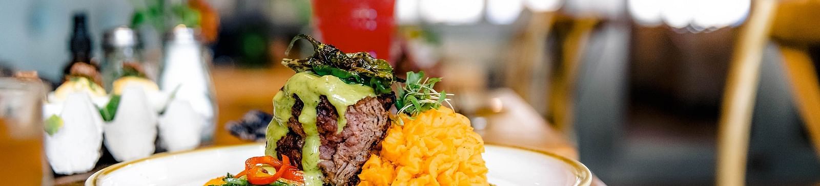A plated meal and a drink in a modern restaurant setting.- The Grand Hotel & Ballroom, McKinney