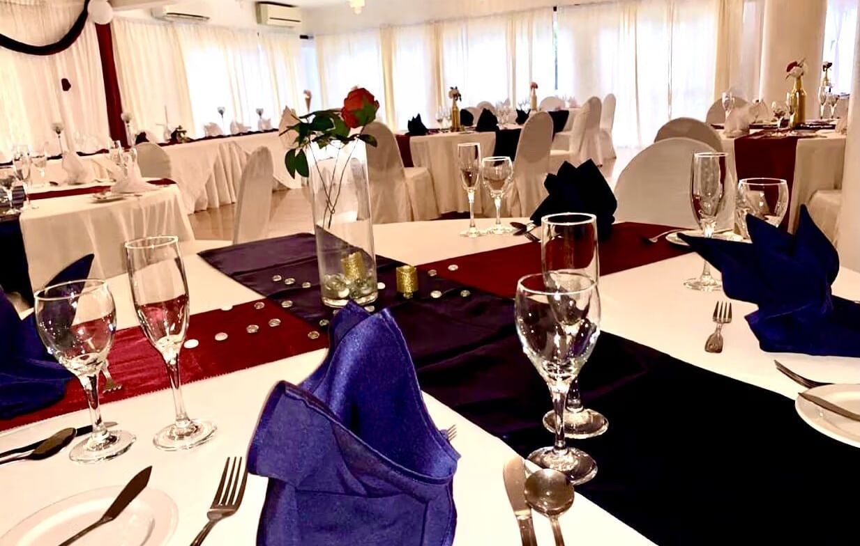 A formal dining table is set with blue and red napkins, glasses, and place settings | Luxor | Altamont Court, Jamaica