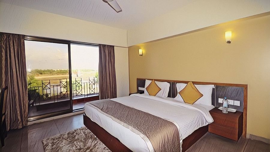 a double bed with side tables and a fan hanging from the ceiling - VITS Kamats Resort, Silvassa