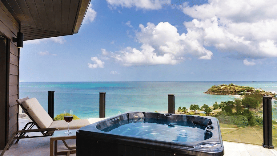 A private terrace with a swimming pool, sun loungers, covered seating area, and panoramic views of the sea and coastline at Suite 35, Tamarind Hills Resort and Villas.