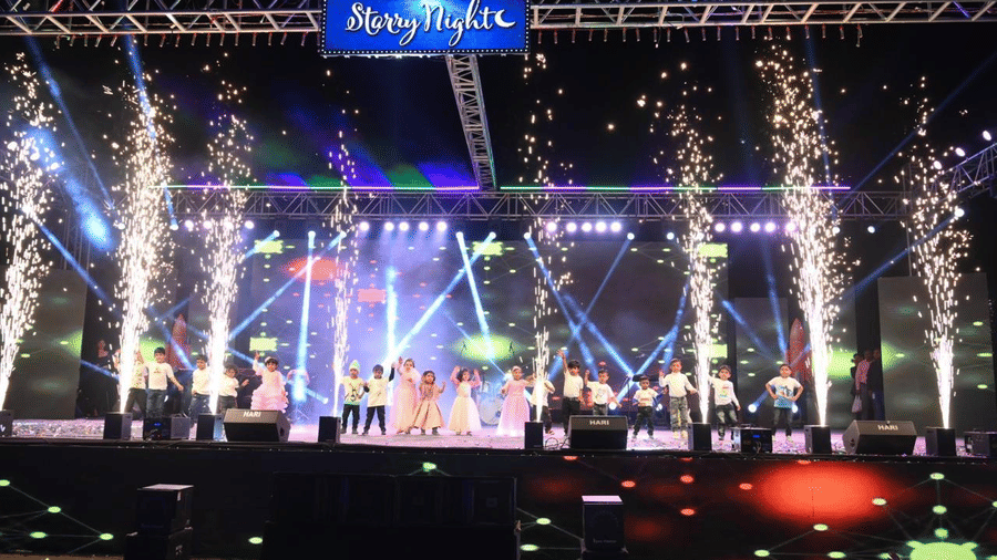 A large concert-style stage with truss structures, overhead lighting, and performance equipment arranged in front.