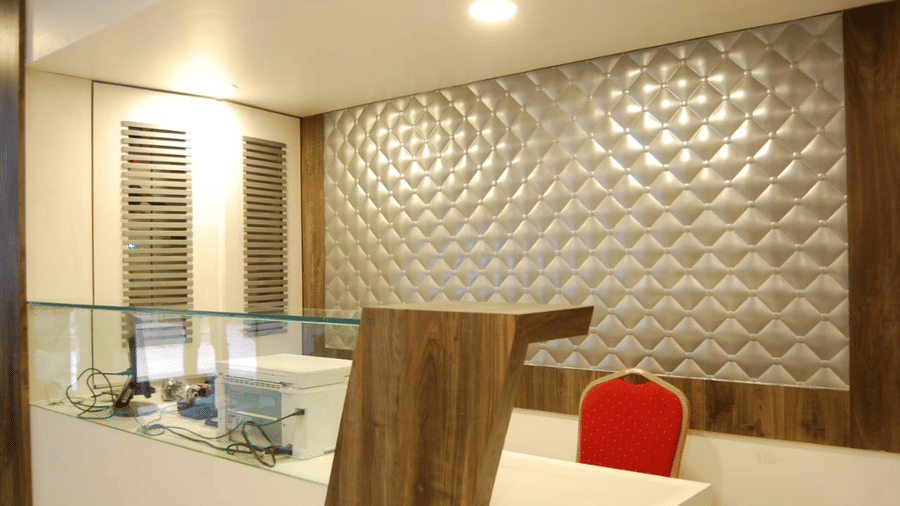 A modern hotel reception desk with a warm wooden panel and illuminated background lighting.