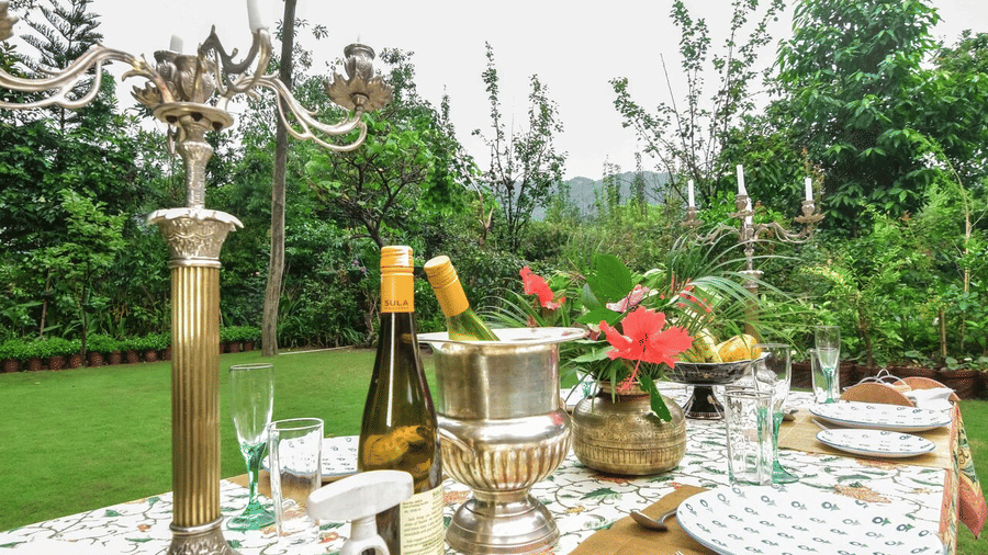 A table set up outdoors at the restaurant of Shaheen Bagh, one of the best fine dining restaurants in Dehradun,  with a lawn area and tree in the distance