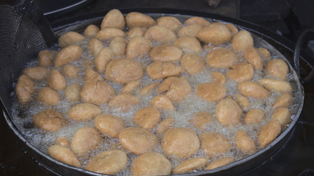 Deep fried dough cutlets in hot oil in a big frying utensil