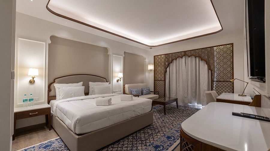 Corner view shot of the Jalrupa Room with a plush double bed placed over a patterned carpet and a common seating area in the corner of the room at Bhagirathi by RDB Atishay.
