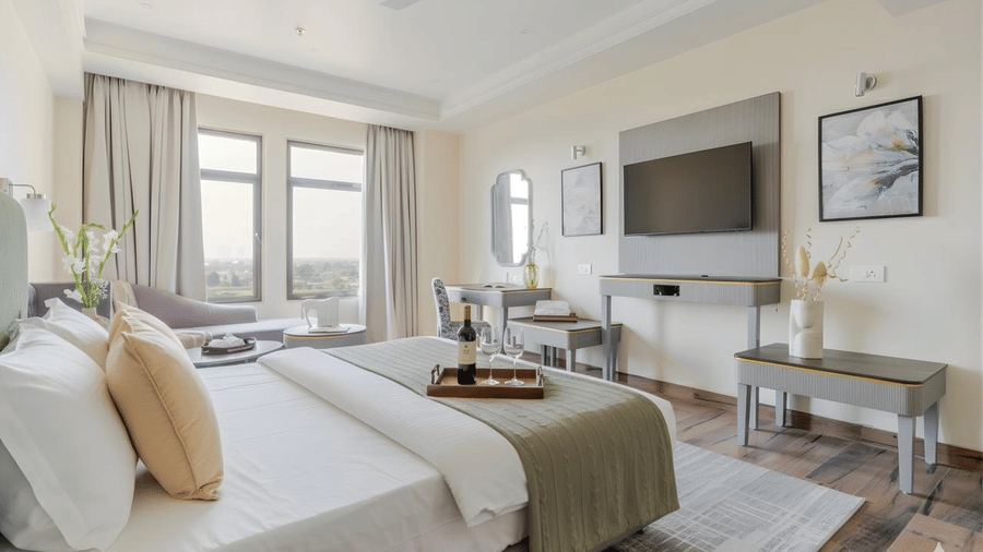 An overhead shot of the Standard Room at Essentia Luxury Hotel and Convention, Nagpur, featuring a double bed placed in front of a wall-mounted television.
