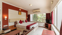 a double bed with side tables and lamps above the bed inside one of the rooms - VITS Presidency Daman