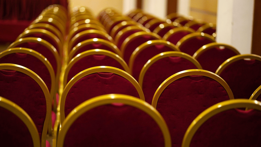 Wide view of empty chairs arranged in neat rows in a large indoor venue, with round, upholstered backs.