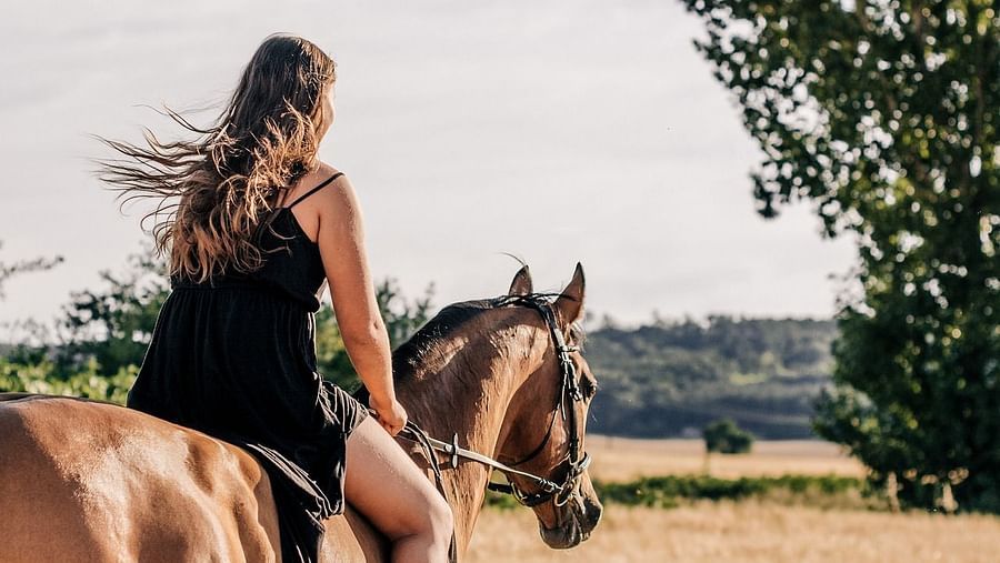 A women is sitting on horse and the horse is 