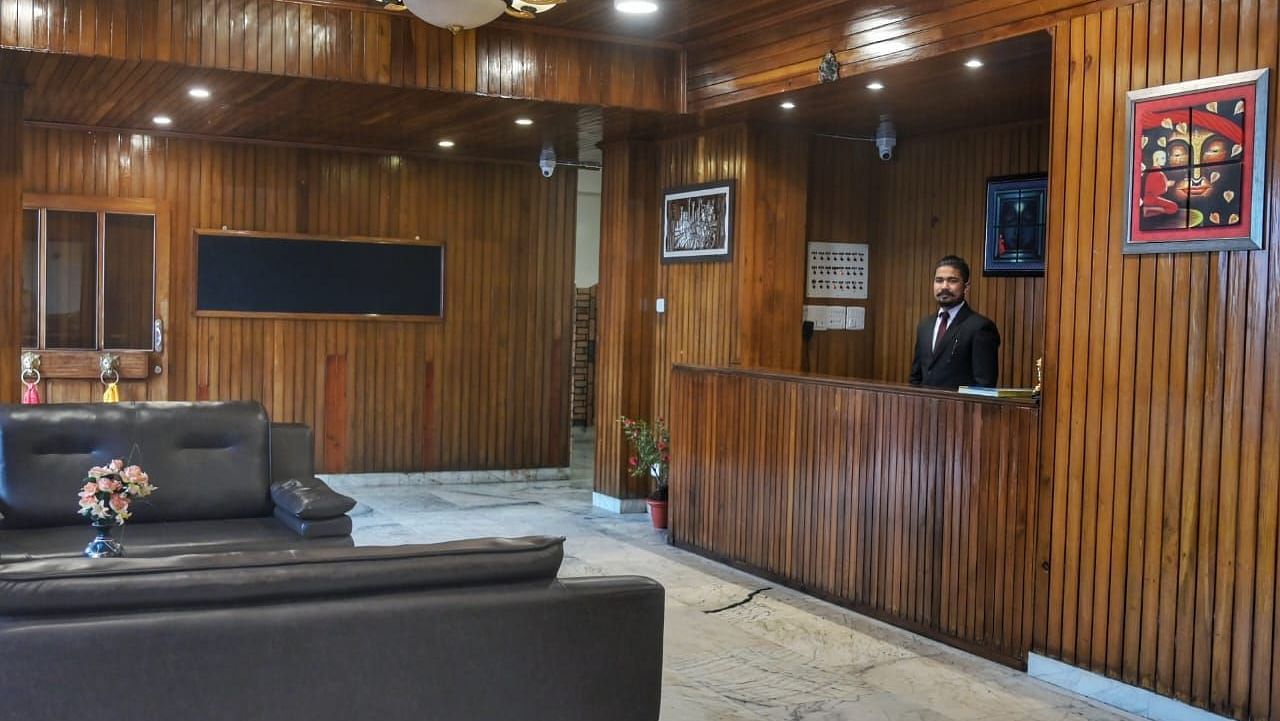An image of the reception with the front desk where a man is standing and the seating area with sofa sets - Sumitel Chiminda, Pelling