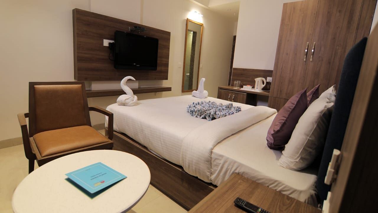 Room at Hotel Mumbai House Express, Udaipur with a double bed, a television and a coffee table and chair