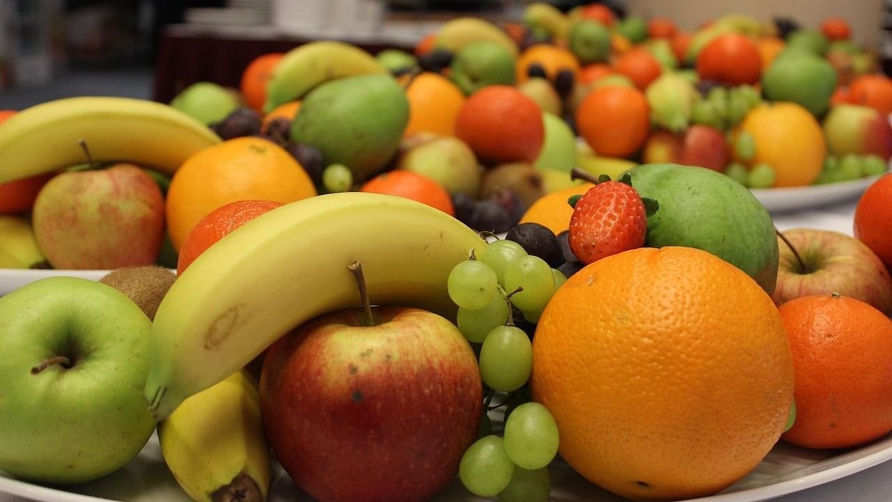 A vibrant assortment of fruits like bananas, apples, grapes, and oranges in a bowl.