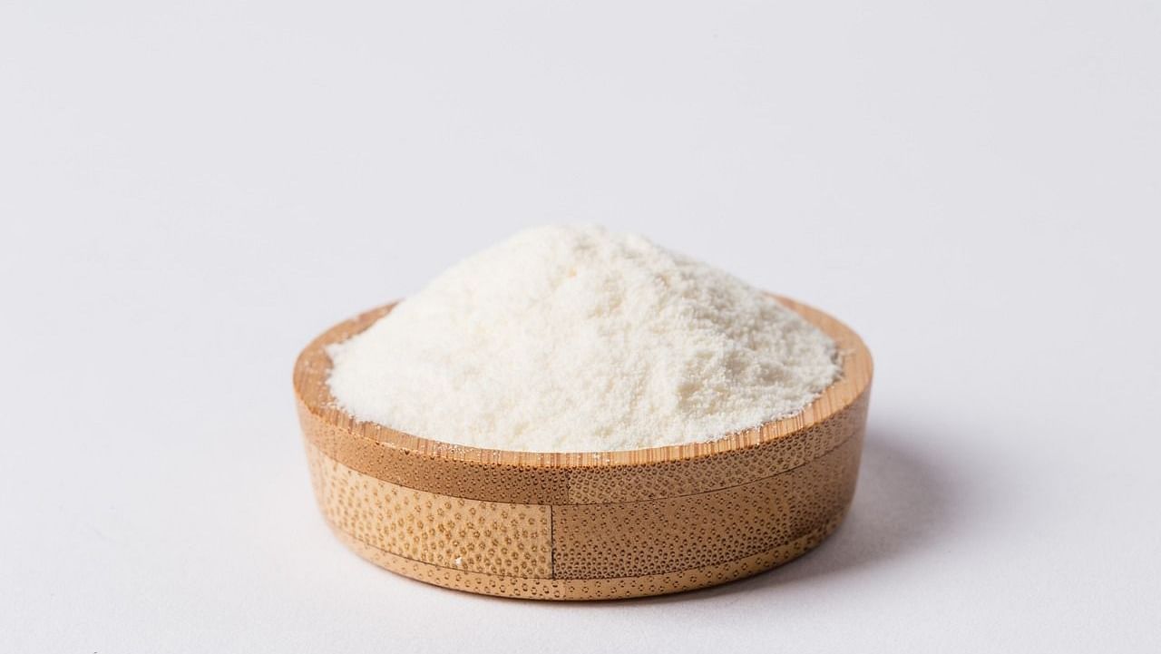 An image of a wooden bowl filled with finely powdered milk, showcasing its smooth texture.