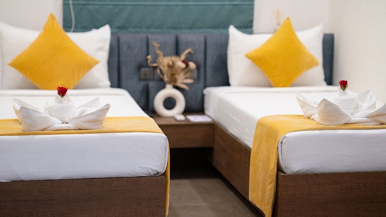 A twin room with two neatly made beds, accented with pillows and a decorative centrepiece on the bedside table at Kyzen Smart Stays.