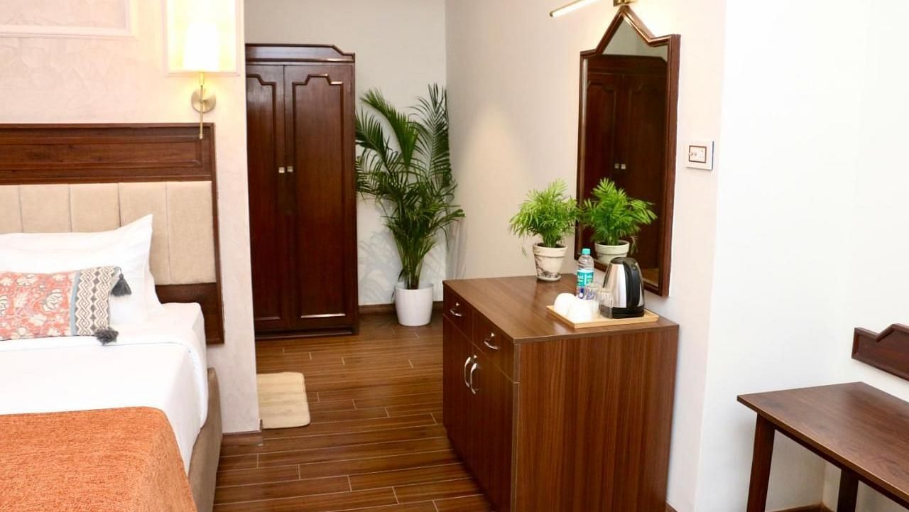 A corner of Luxury Twin Room in Nalapad's Hotel Bangalore International, featuring wooden furniture and plants.