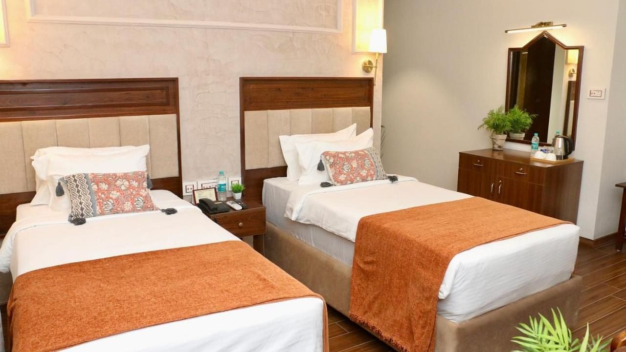 Classic Twin Room at Nalapad Hotel Bangalore International featuring two neatly made single beds with warm-toned decor, a vanity area, and modern amenities.