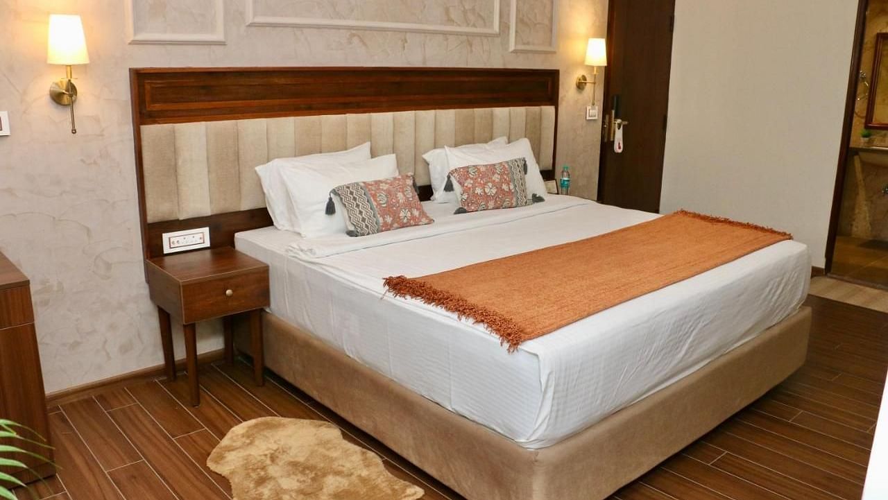 A neatly made bed with white linens and decorative pillows of Luxury Junior Suite at Nalapad Hotel Bangalore International.