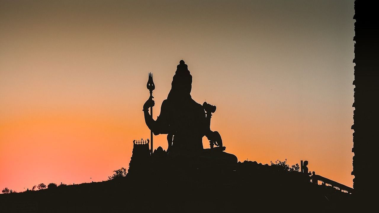 Striking silhouette of a Lord Shiva statue against a vibrant sunset sky - Kumarakom