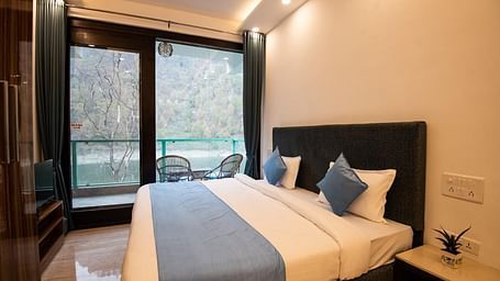 A compact bedroom with a bed placed against the wall, a ceiling fan, and a view through large windows.