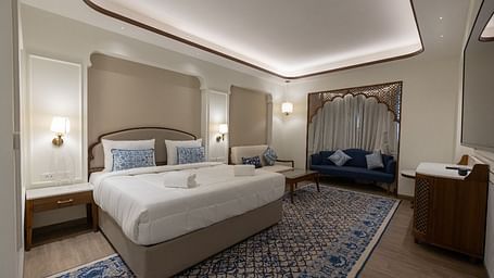 Corner view shot of the Mandakini Room featuring a plush double bed along with a long patterned carpet on the floor at Bhagirathi by RDB Atishay.
