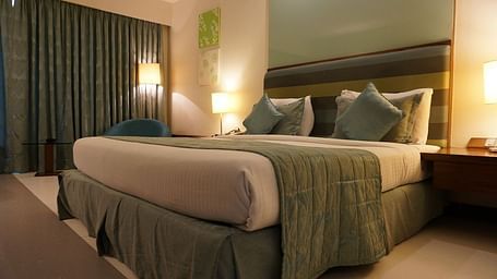 Image of a bedroom with a large bed, side tables, and lamps.