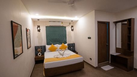 A room with a double bed, decorative pillows, wall art, and warm lighting, offering a welcoming atmosphere at Hotel Kyzen Smartstays – Smart, Reliable, Kyzen