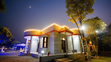 Uniquely shaped building exterior of Lime Tree Hotels & Service Apartment Private Limited illuminated with warm lighting at night.