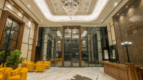 Hotel lobby with crystal chandelier, yellow tub chairs, marble flooring and reception desk with Polo Towers branding at Polo Hotel, Agartala.