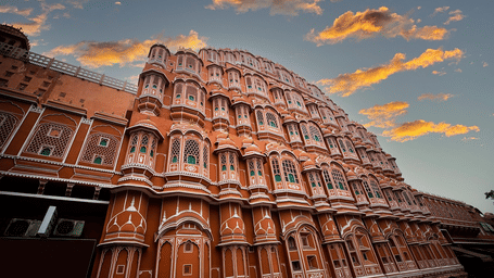 Exterior view of a historic pink building photographed at sunset with clouds in the sky.