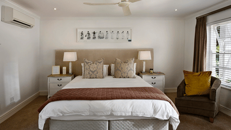 A double bed with a ceiling fan hanging over it in a bedroom.