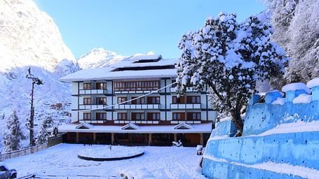 Image of the hotel covered with snow with mountains on either side and few trees   | Yashshree Lachung