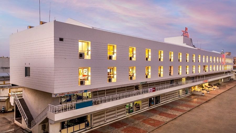 An exterior view at Angel Lords Eco Inn Amreli with many illuminated windows at dusk.