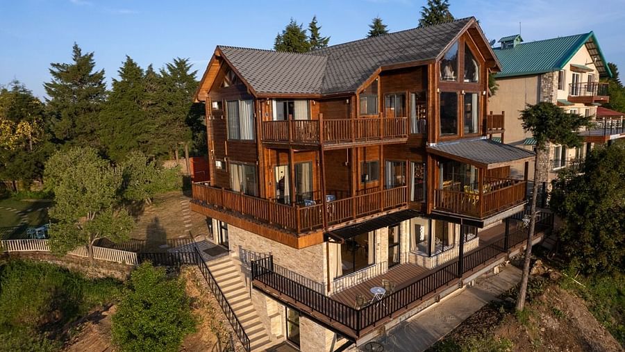 A image of a attic style facade with exterior stairs and balconies amidst the lush green mountain | Avalon Cottages, Kanatal