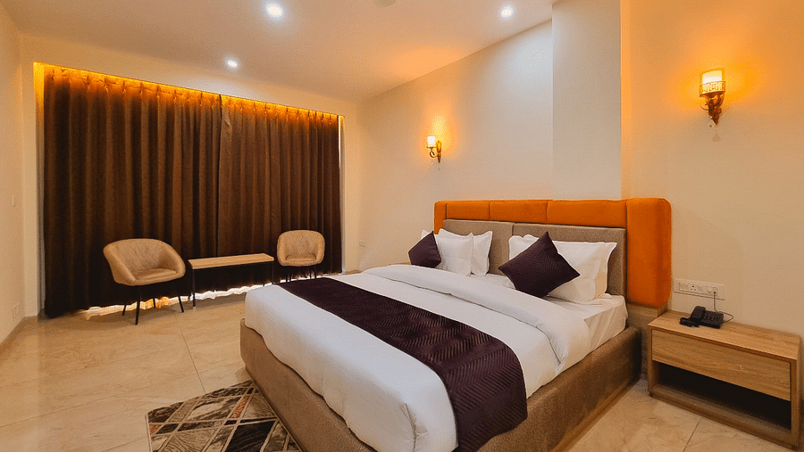 Deluxe Room with bed, a besdie table and chairs in the corner at Pines and Peaks, Dalhousie 