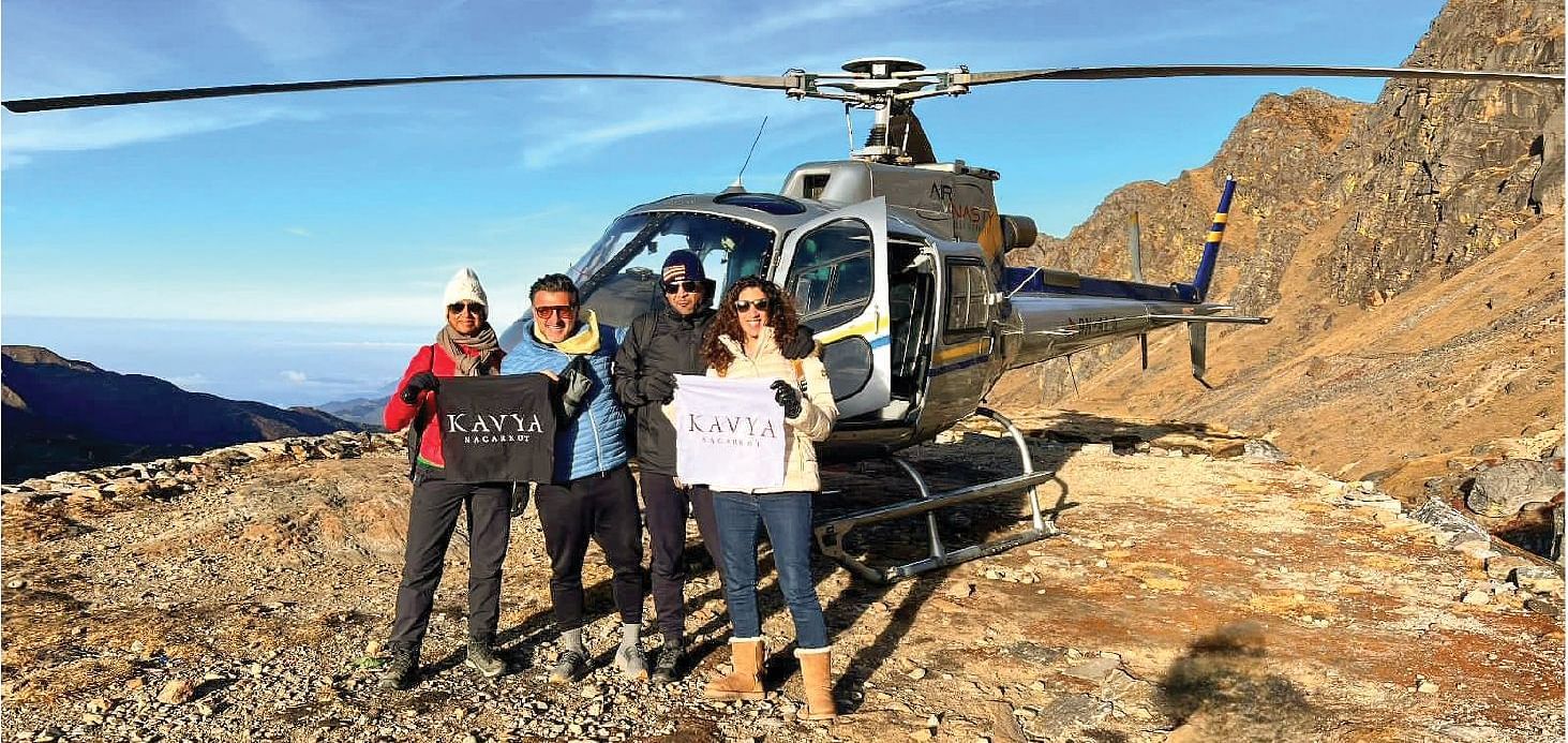Group of tourists standing next to a helicopter in a mountainous area.