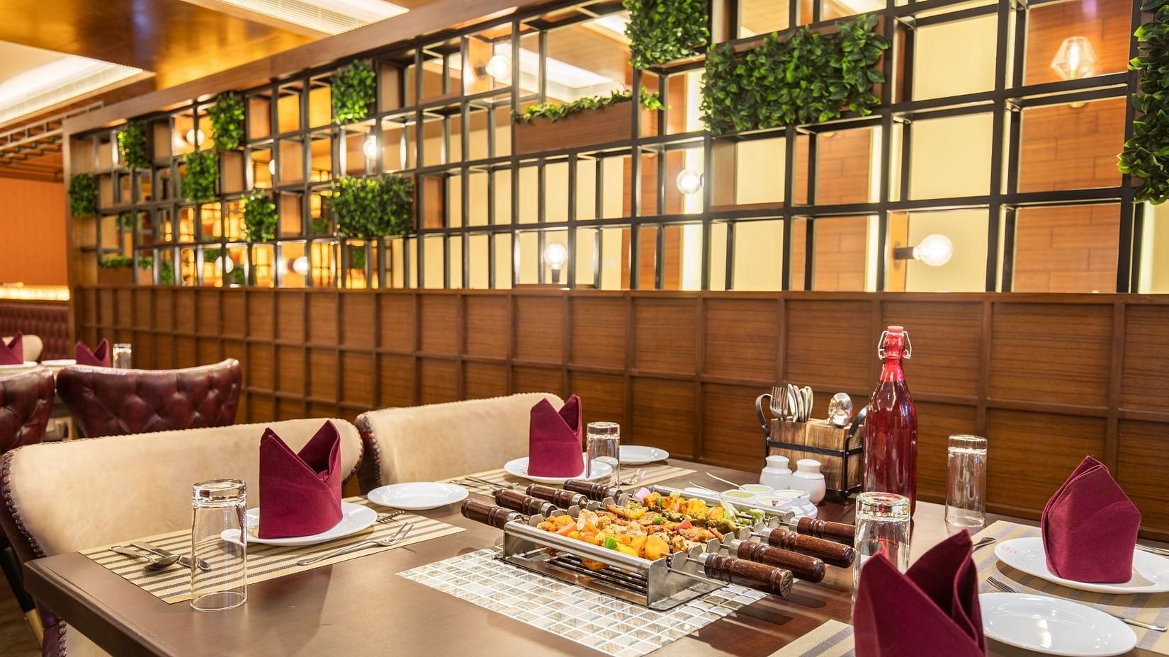 Elegant dining area at Jenneys Residency featuring a neatly set table, comfortable chairs, and a stylish wall adorned with green planters