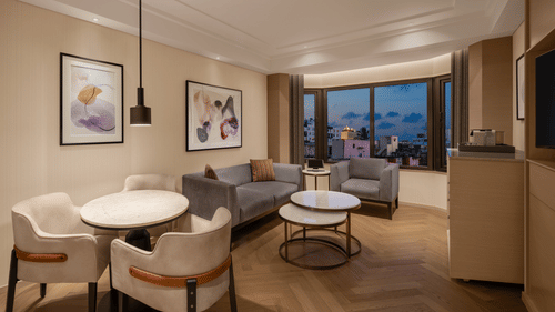 Elegant living area of a spacious suite room at The Residency Chennai, showcasing a stylish sofa set, framed artwork on the walls, and a round table.