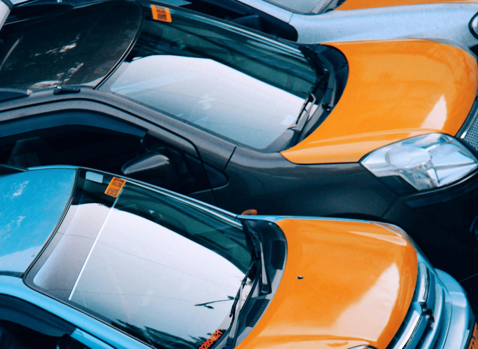 A row of car parked side-by-side in a lot.