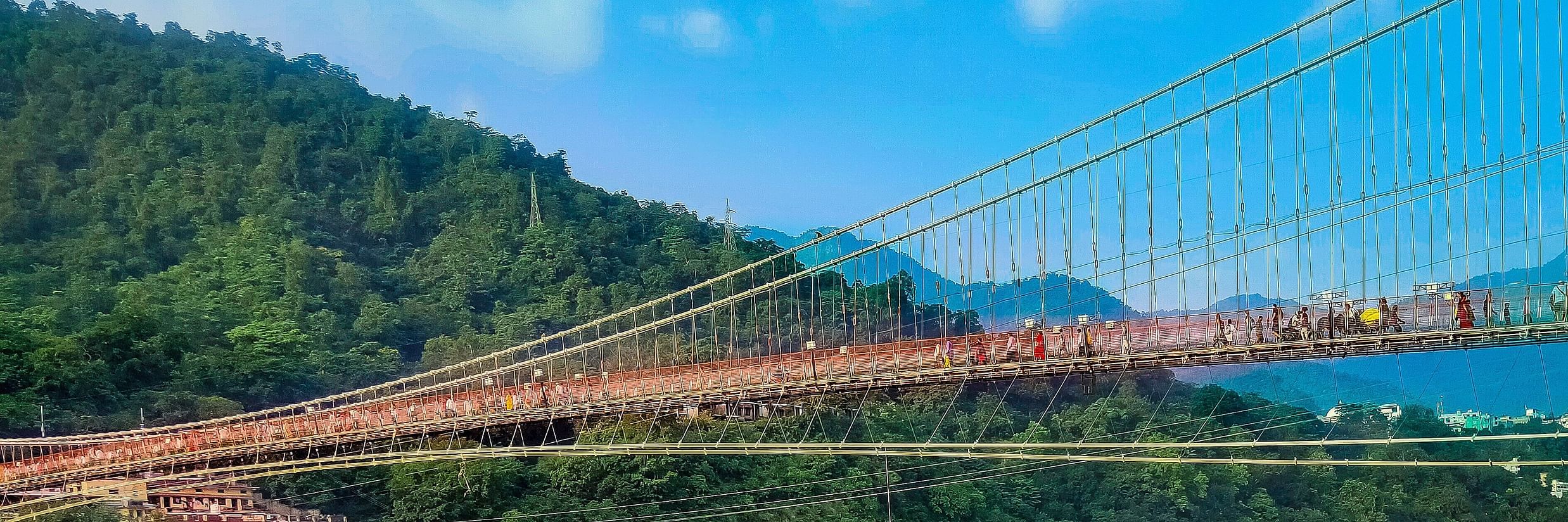 A man sitting on a ledge near Ram Jhula bridge @ Lamrin Boutique Cottages, Rishikesh