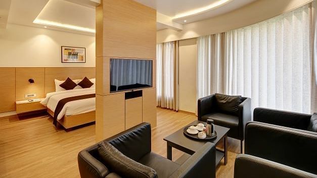 Wide view of the luxury room with a double bed and sofa seating at Hotel Mumbai House, Ghansoli