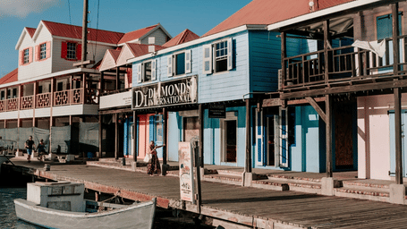 A waterfront road featuring colorful buildings and boats docked at the pier on a sunny day at the Tamarind Hills Resort and Villas, Antigua.