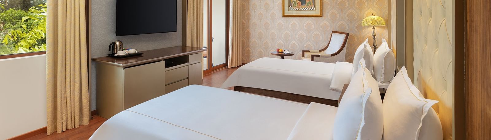 A cosy bedroom with twin beds, large windows, and a scenic outdoor view – Kaldan Samudra, one of the top ECR resorts