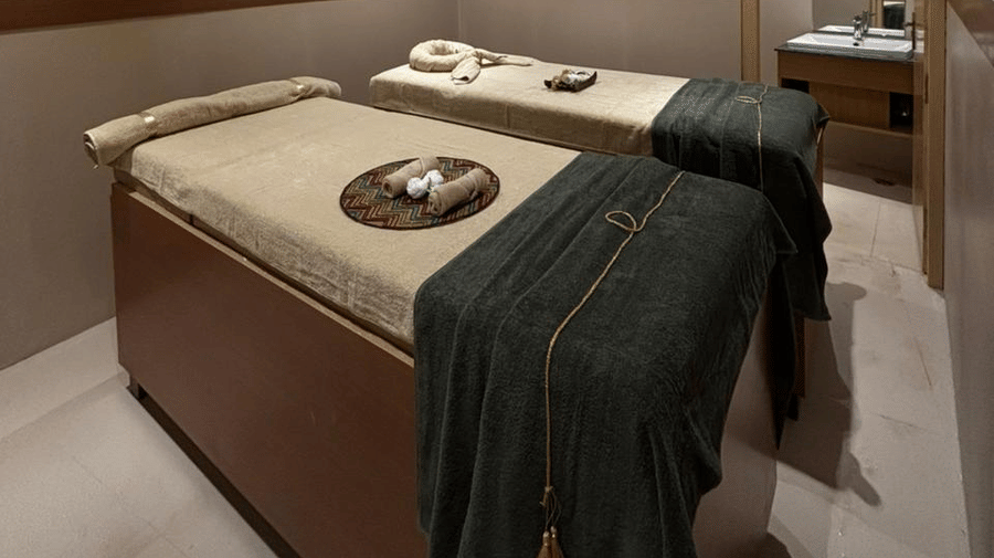 Couple therapy room at ABN Sarovar Portico, Jim Corbett featuring two similar looking bed which towels and spa products each, and the room alspo have an air-conditioner. 